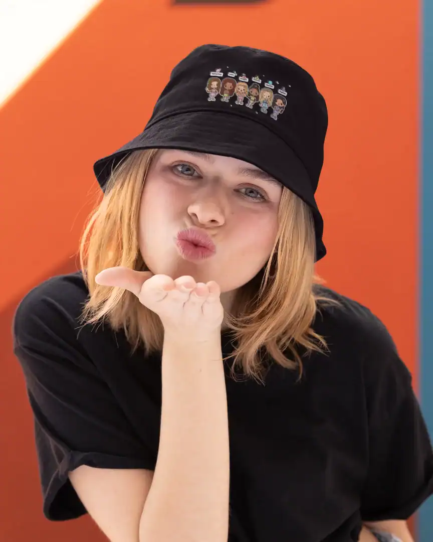model blowing a kiss wearing black katseye bucket hat with orange background